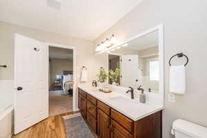 Bathroom with wood finished floors, double vanity, toilet, and ensuite bathroom