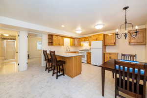 Kitchen with white appliances, under cabinet range hood, a peninsula, open shelves, and light countertops