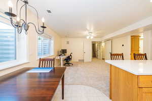 Dining space featuring a desk, light colored carpet, ceiling fan, and stairway