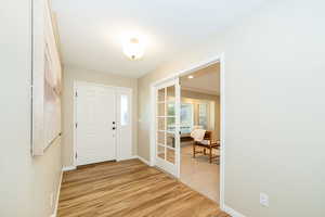 Entrance foyer featuring light wood finished floors, french doors, and baseboards
