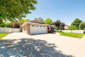 View of front of home with brick siding, concrete driveway, an attached garage, and a chimney