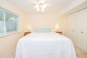 Bedroom featuring light colored carpet, a closet, and a ceiling fan