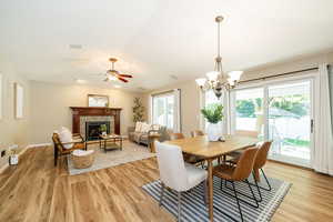 Dining room featuring light wood finished floors, a stone fireplace, a chandelier, and baseboards