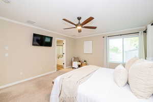 Bedroom with ornamental molding, baseboards, light carpet, ensuite bathroom, and ceiling fan