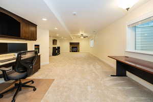 Office featuring light carpet, a fireplace, recessed lighting, baseboards, and a ceiling fan