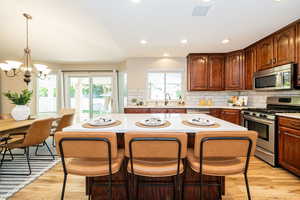 Kitchen with stainless steel appliances, light countertops, a kitchen island, decorative backsplash, and a kitchen bar