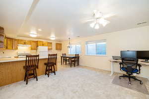 Kitchen featuring white appliances, under cabinet range hood, a sink, a peninsula, and light countertops