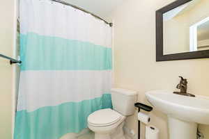 Full bath with toilet, a sink, and curtained shower