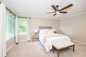 Bedroom with ornamental molding, light carpet, baseboards, and ceiling fan