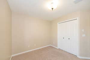 Unfurnished bedroom with light colored carpet, baseboards, and a closet