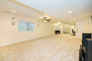 Unfurnished living room featuring light carpet, a ceiling fan, baseboards, recessed lighting, and a textured ceiling
