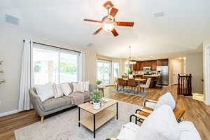 Living area with lofted ceiling, light wood-style floors, a chandelier, baseboards, and a ceiling fan