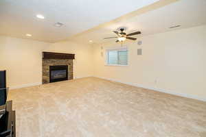 Unfurnished living room featuring a stone fireplace, carpet floors, a ceiling fan, baseboards, and recessed lighting