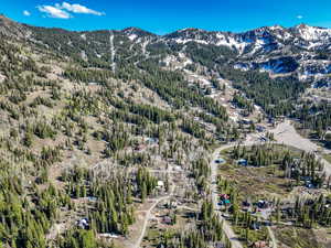 Aerial view of property's location featuring a mountain backdrop and a forest