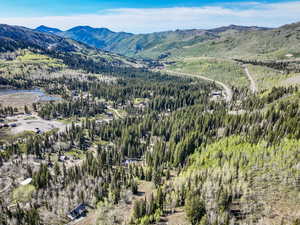 View of mountain backdrop featuring a forest and a large body of water