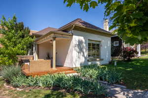 View of side of home with stucco siding, a yard, and a chimney