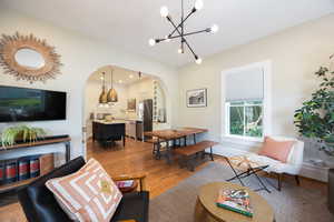 Living area with arched walkways, a chandelier, light wood-style flooring, and baseboards