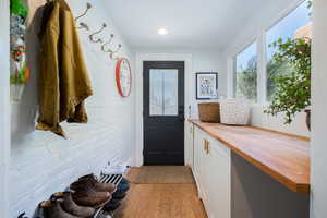 Mudroom with light wood-style flooring and brick wall