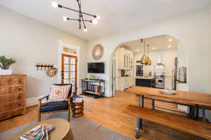 Living area featuring arched walkways, a chandelier, baseboards, and light wood-style flooring