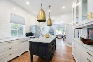 Kitchen featuring a sink, freestanding refrigerator, white cabinets, a chandelier, and a kitchen island