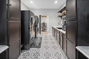 Laundry area featuring stacked washer and clothes dryer, light tile patterned floors, recessed lighting, and baseboards