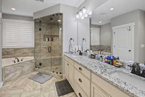 Full bathroom with double vanity, a jetted tub, a steam shower, marble finish flooring, and recessed lighting