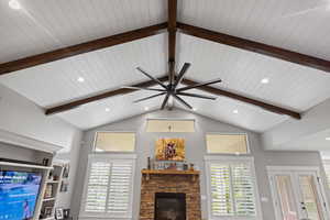 Living room with ceiling fan, a fireplace, plenty of natural light, and wooden ceiling