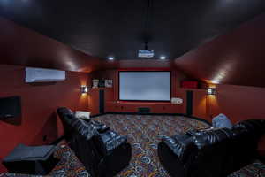 Carpeted home theater with a wall unit AC and lofted ceiling