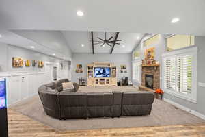 Living room with ceiling fan, a stone fireplace, wood finished floors, recessed lighting, and baseboards