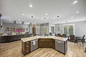 Kitchen with dishwasher, a sink, open floor plan, light wood-style floors, and recessed lighting