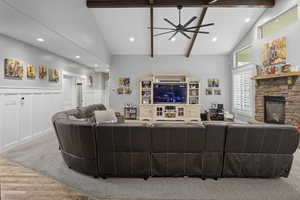 Living area featuring wood finished floors, a stone fireplace, a ceiling fan, beam ceiling, and recessed lighting