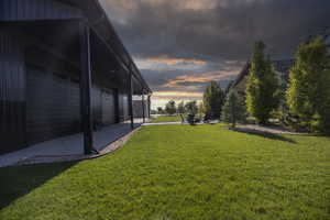 View of grassy yard with a pool house and a patio area