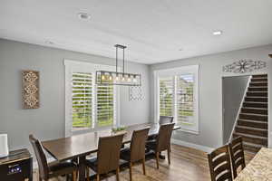 Dining space featuring wood finished floors, stairway, baseboards, and recessed lighting