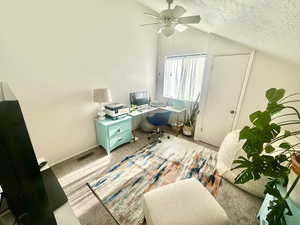 Home office with lofted ceiling, ceiling fan, a textured ceiling, and carpet flooring