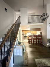 Living area with a chandelier, stairway, a towering ceiling, wood finished floors, and baseboards