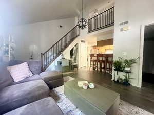 Living area with a high ceiling, wood finished floors, stairway, ceiling fan, and baseboards