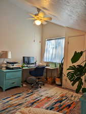 Carpeted home office featuring a textured ceiling, vaulted ceiling, and ceiling fan
