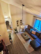 Living area featuring dark wood-style floors, high vaulted ceiling, a textured ceiling, and a chandelier