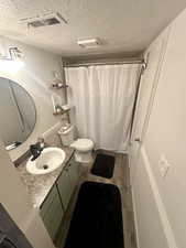 Full bath featuring a textured ceiling, vanity, wood finished floors, toilet, and a shower with curtain