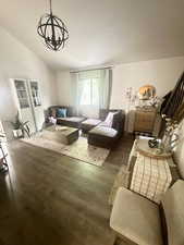 Living room featuring wood finished floors, a chandelier, and vaulted ceiling