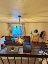 Living room with a textured ceiling, wood finished floors, and a chandelier