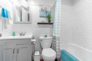 Bathroom featuring vanity, toilet, and shower / tub combo with curtain