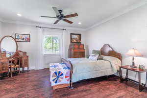 Bedroom with wood finished floors, crown molding, baseboards, recessed lighting, and ceiling fan