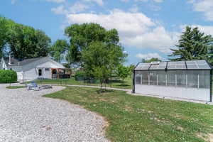View of yard featuring a greenhouse, a fire pit, and an outdoor structure