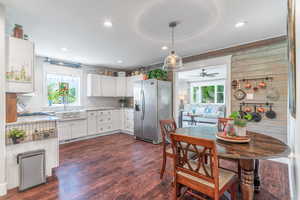 Kitchen featuring stainless steel fridge with ice dispenser, white cabinetry, ceiling fan, light stone countertops, and tasteful backsplash