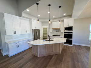 Kitchen featuring decorative backsplash, hanging light fixtures, white cabinetry, appliances with stainless steel finishes, and light quartz countertops
