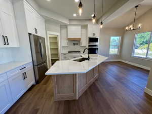 Kitchen featuring tasteful backsplash, light quartz countertops, custom white cabinets, vaulted ceiling, and recessed lighting