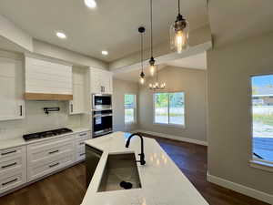 Kitchen with pendant lighting, custom white cabinetry,  backsplash, and light stone countertops