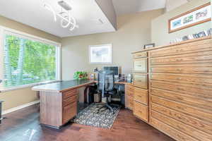 Office space with dark wood-style flooring and baseboards
