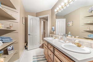 Full bath featuring double vanity and baseboards